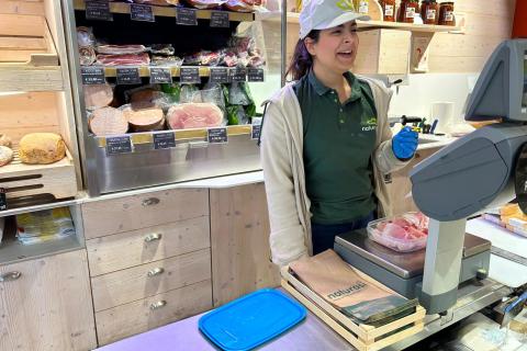 La gastronoma di Naturasì di via Melzo fa la tara del contenitore mentre pesa il prosciutto.