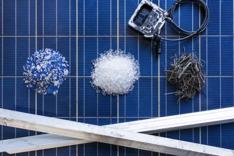 Componenti recuperati da un pannello fotovoltaico con la tecnologia 9PV: frammenti di celle fotovoltaiche, granuli di vetro, fili di rame, profili in alluminio e scatola di giunzione con cavi, disposti su una superficie di pannelli solari.